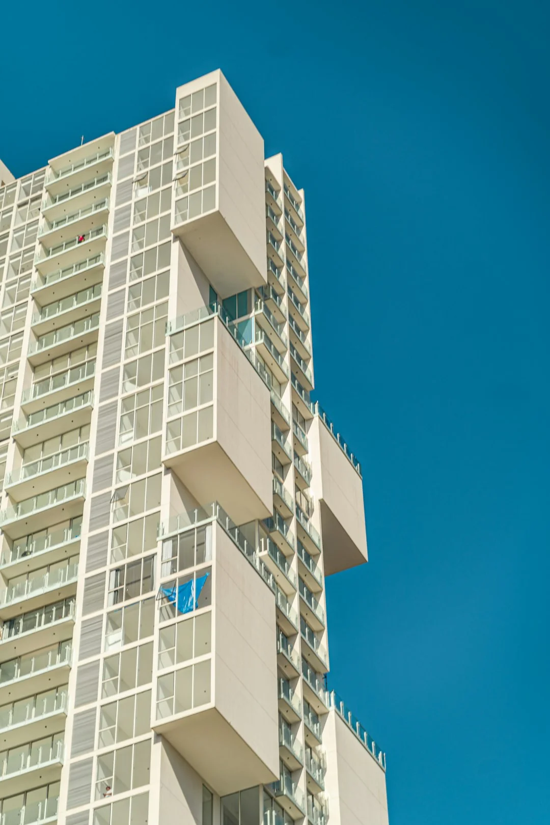Deux employés nettoient les vitres d’une façade d’immeuble en verre à l’aide d’une plateforme élévatrice, afin d’améliorer l’esthétique du bâtiment.